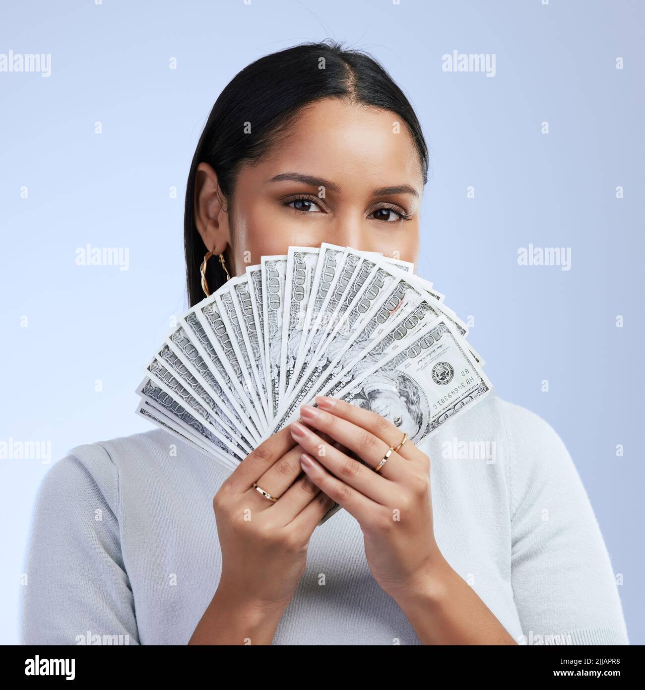 Zeigt mir das Geld. Eine junge Frau, die Banknoten über ihr Gesicht hält. Stockfoto