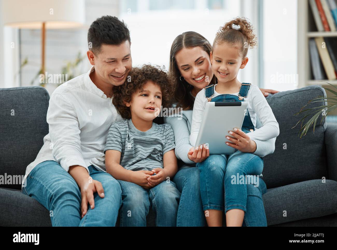 Familienzeit ist eine liebevolle Zeit. Eine junge Familie verbringt Zeit miteinander, während sie ein digitales Tablet nutzt. Stockfoto