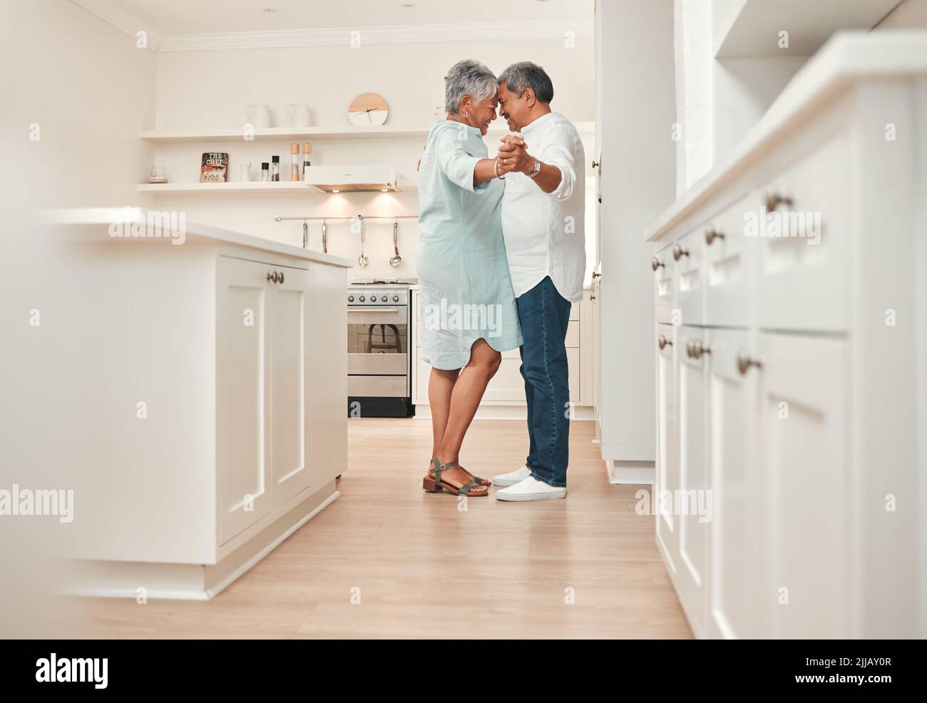Ich sagte, bis sie alt und grau waren... ein reifes Paar, das zu Hause in der Küche tanzte. Stockfoto