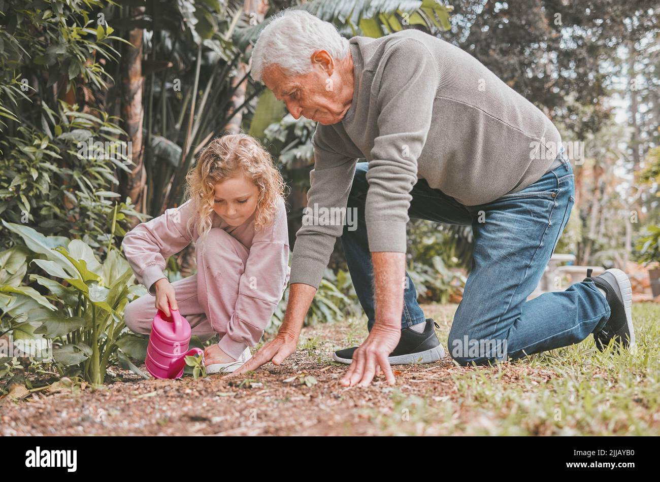 Lernen, Garten ist eine ganze Menge Spaß. Ein entzückendes kleines Mädchen im Garten mit ihrem Großvater. Stockfoto