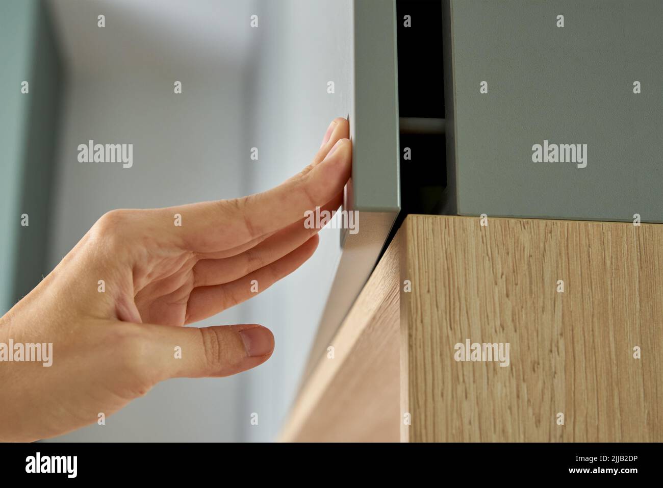 Weibliche Hand offenen Küchenschrank, Schranktür in Küchenmöbeln Stockfoto