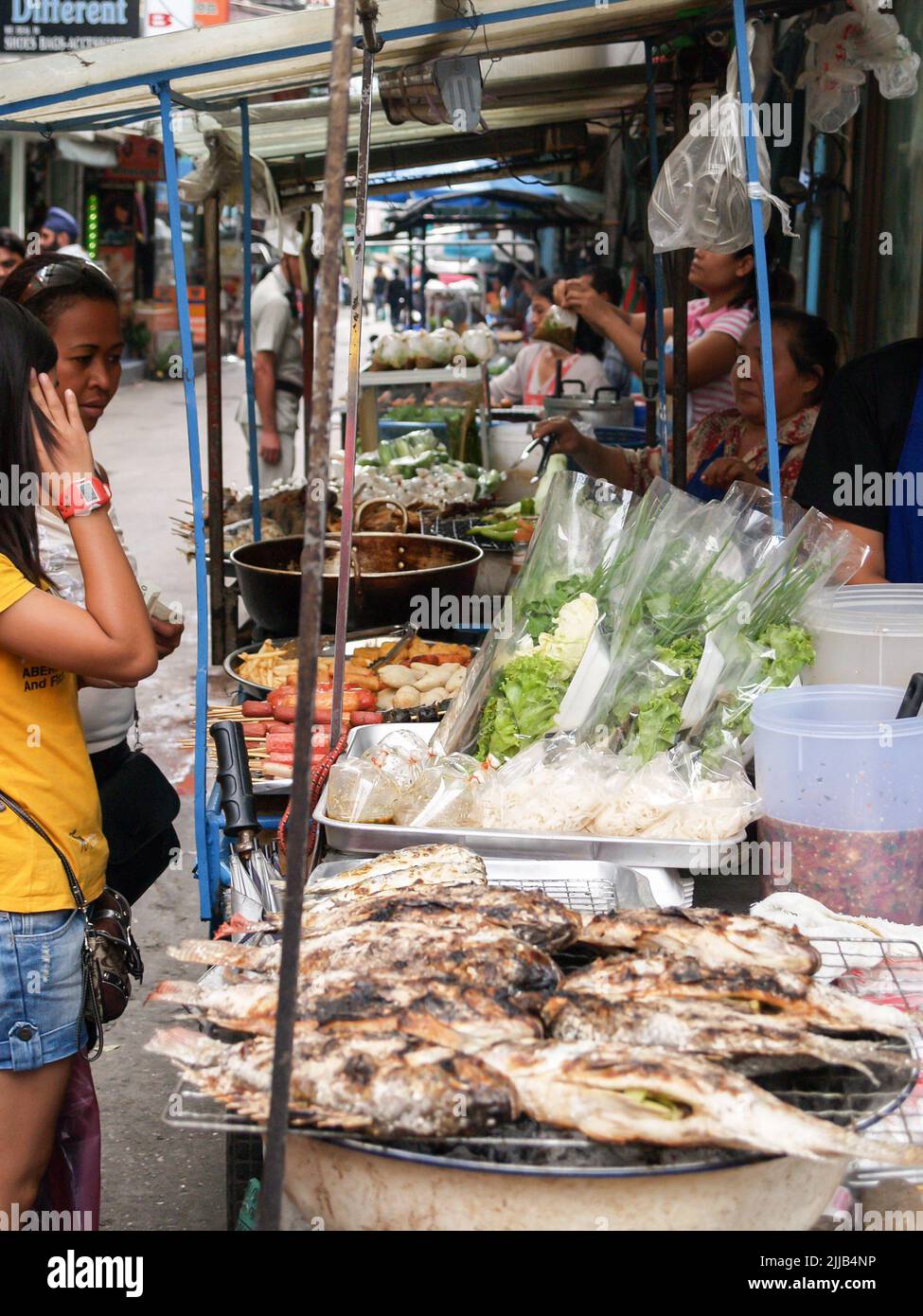 Bangkok Thailand - August 10 2007; Street Food wird gekocht, während junge Frauen zusehen Stockfoto