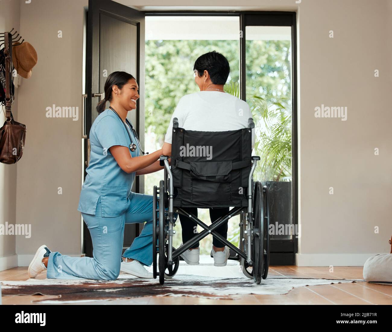 Verstehen Sie die Währung einer Hand voller Liebe. Eine junge Krankenschwester, die sich im Rollstuhl um eine ältere Frau kümmert. Stockfoto