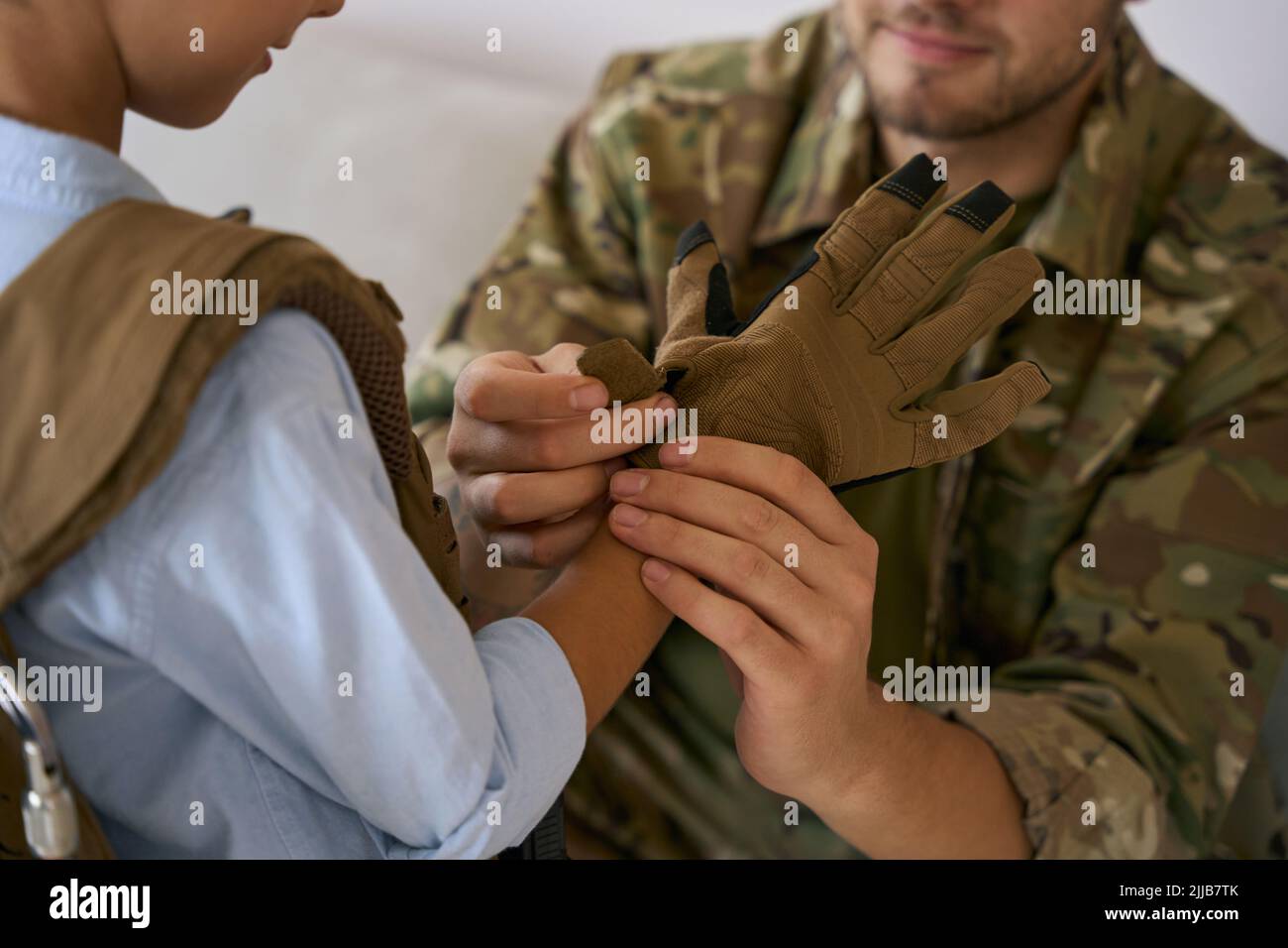 Fürsorglicher Vater im militärischen Handschuh mit Kinderhand Stockfoto