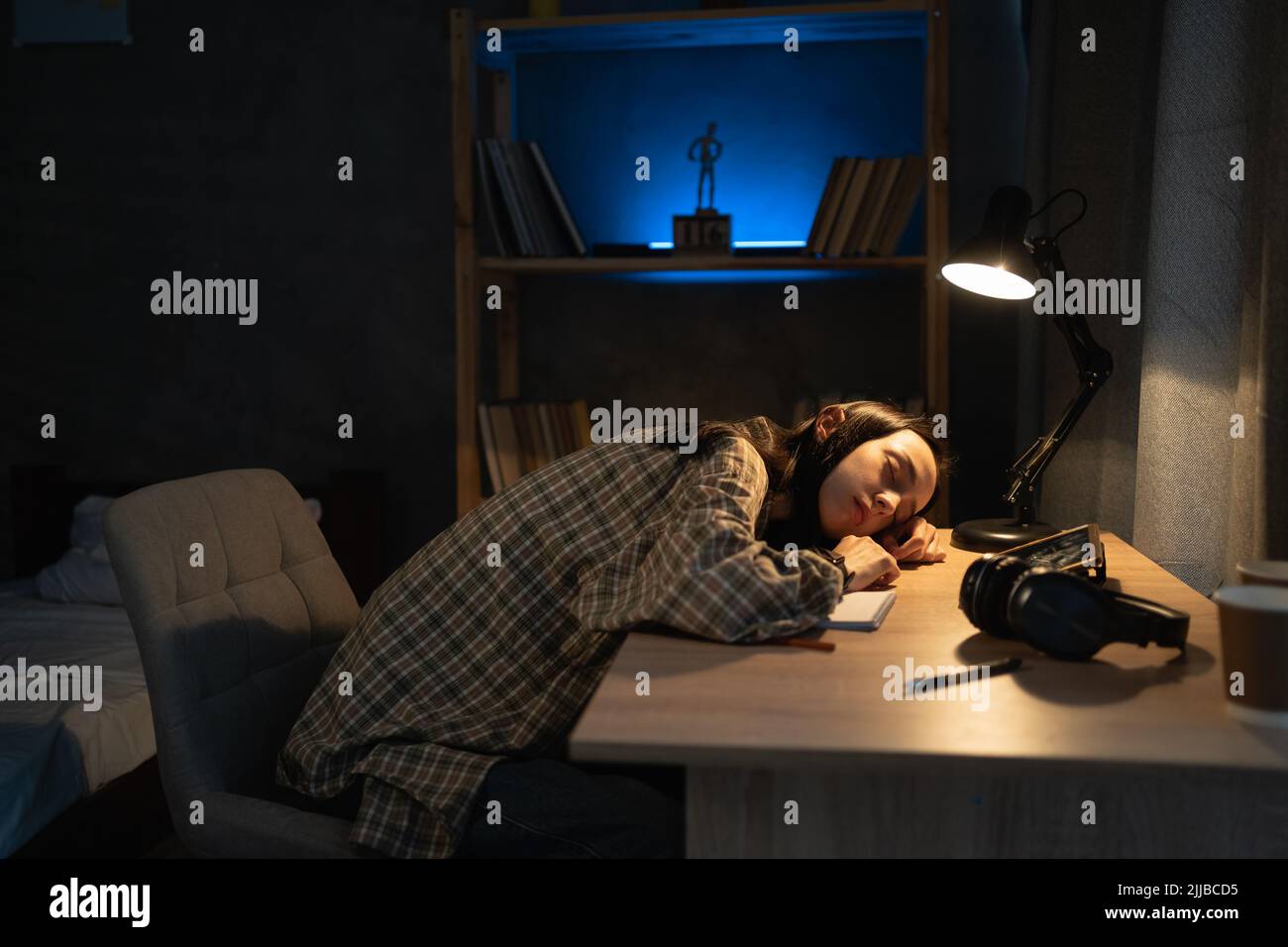 Müde Asienstudentin schläft auf dem Schreibtisch, nachdem sie lange Bücher studiert und gelesen hat, Bildung, Freiberufler, Überarbeit und Menschen Stockfoto