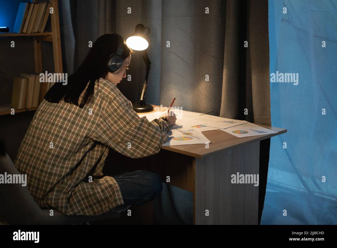 Asiatische Studentin, die nachts zu Hause studiert, mit Grafiken und Diagrammen für ein neues Projekt, Überstunden und Studium arbeitet Stockfoto