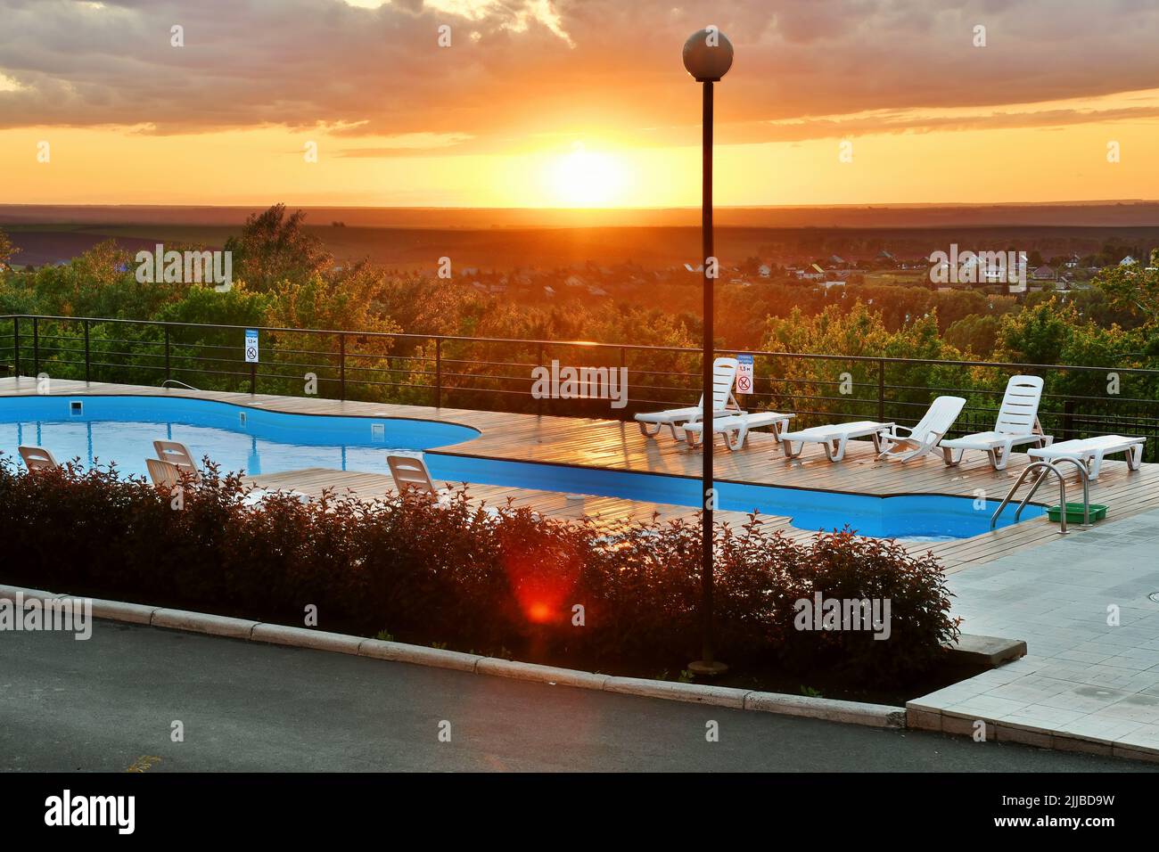 Sonnenuntergang über dem Hügel und Hotel mit Pool und Liegen. Entspannung, Reisen, Freizeitaktivitäten Stockfoto