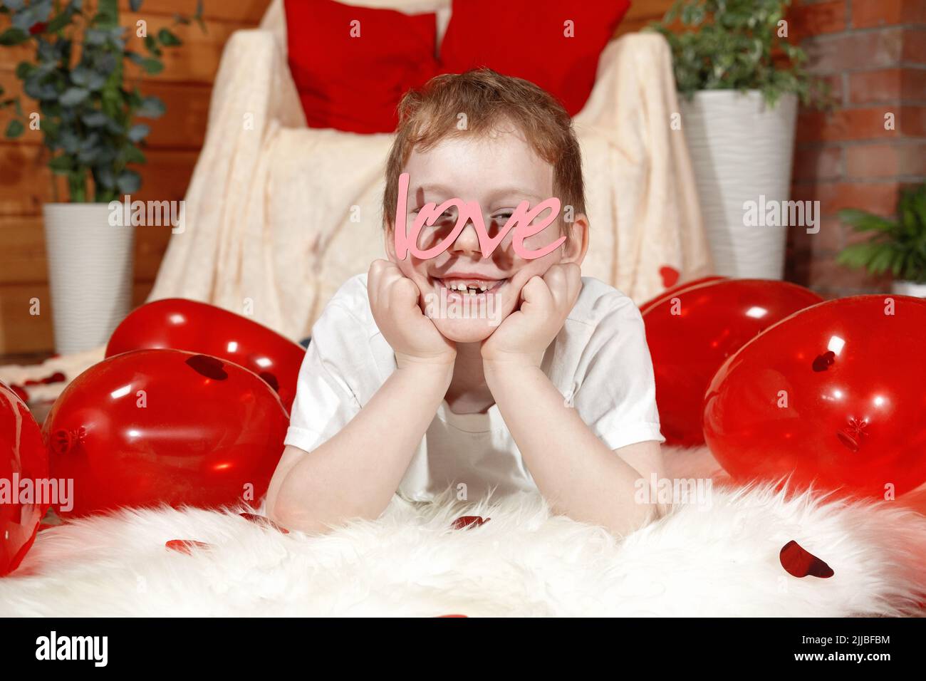 Valentinstag Kinder oder Kinder. Niedlichen fröhlichen kleinen Jungen mit roten Ballons in Form eines Herzens und Text Liebe in Form einer Brille, auf Valentine' Stockfoto