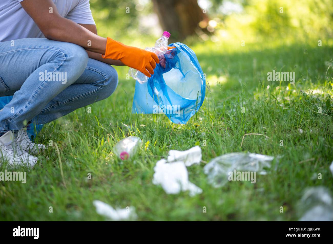 Der Mann hockte seitlich mit einem Müllbeutel im Freien vor die Kamera Stockfoto