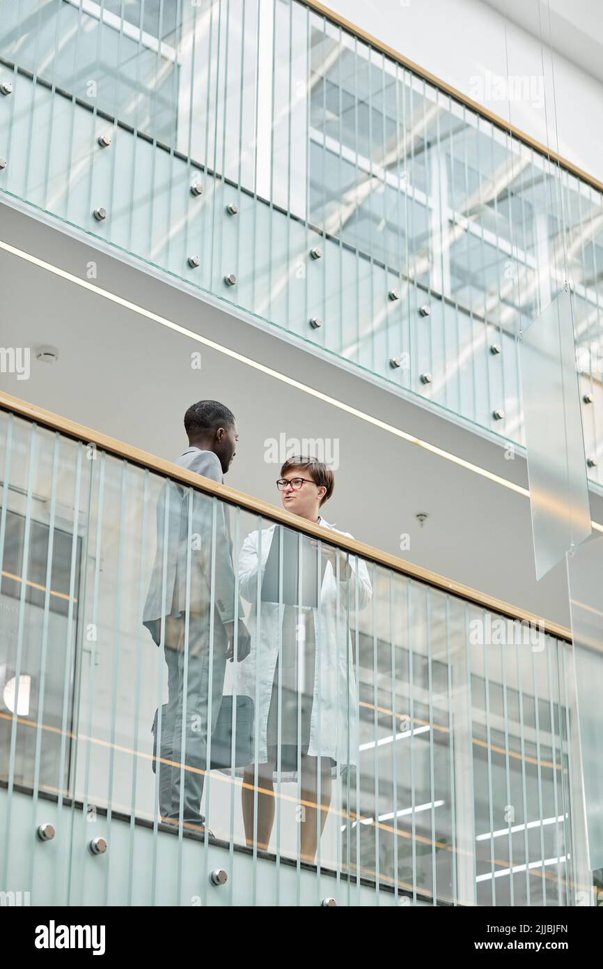 Grafisches Porträt von zwei Geschäftsleuten, die auf dem Balkon in einem modernen Bürogebäude mit Glaselementen stehen Stockfoto