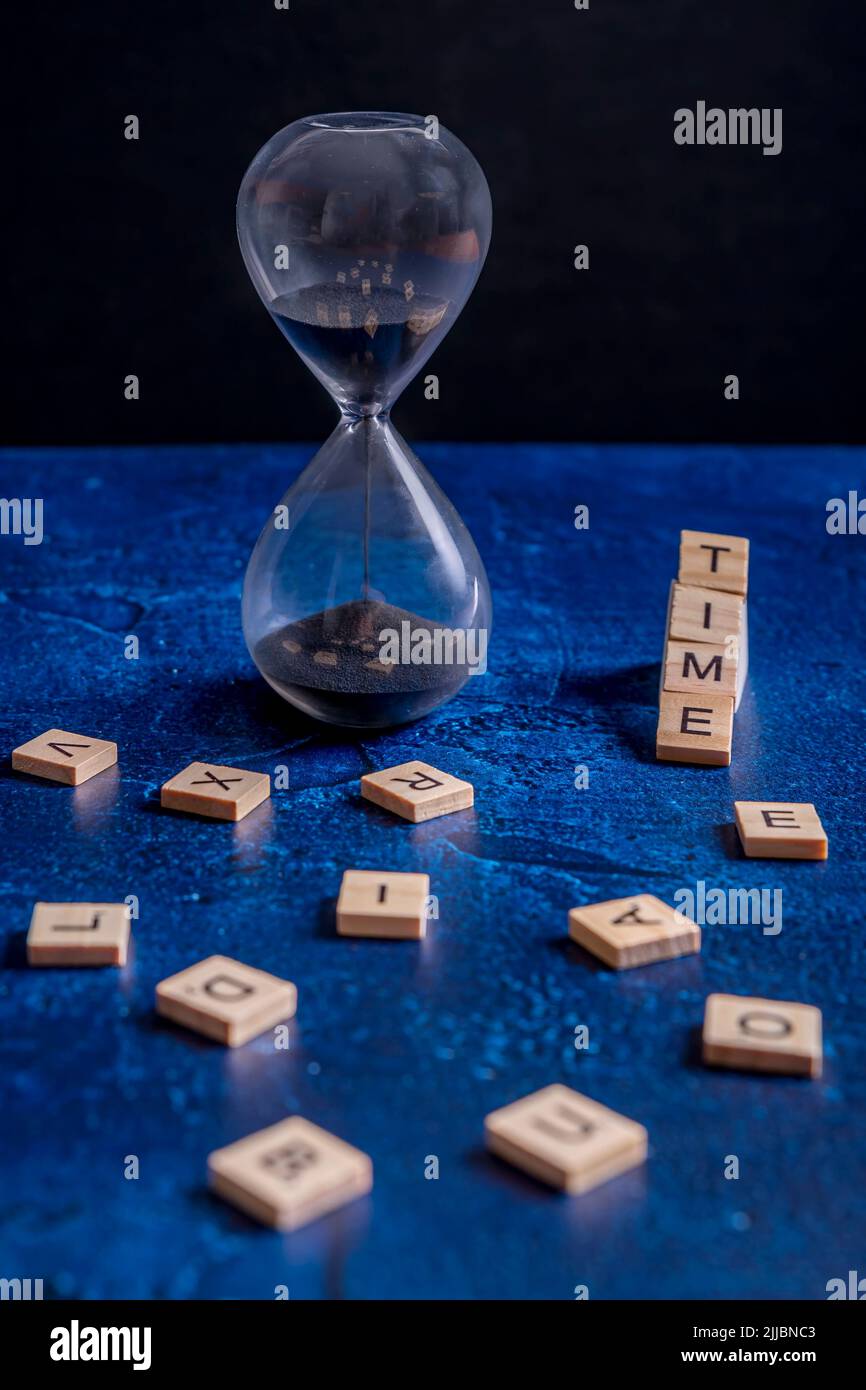 Eine Sanduhr mit schwarzem Sand und dem Wort 'Zeit' daneben Stockfoto