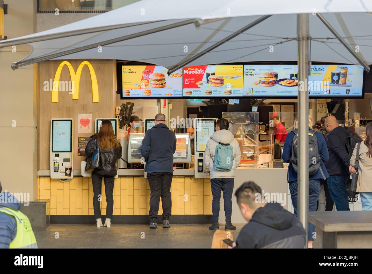 Menschen, die über Bildschirme Lebensmittel und Kaffee zum Mitnehmen bestellen oder nur McDonald's-Geschäfte in Sydney, New South Wales, Australien, mitnehmen Stockfoto