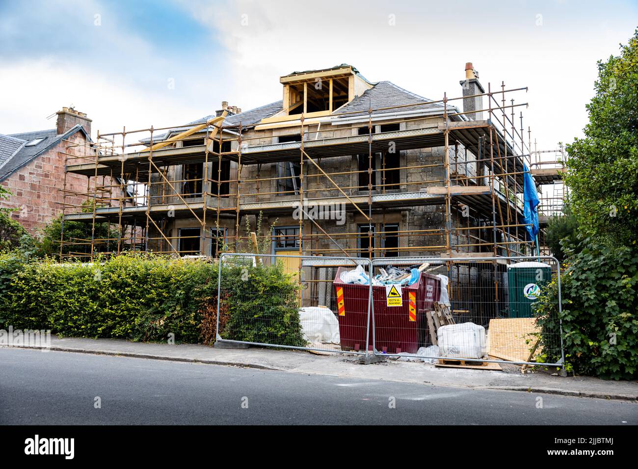 Erste fit und Modernisierung des alten Gebäudes komplett gerüstet, mit Loft-Umbau und überspringen mit Bauherren Abfälle hinter Hecke temporären Zaun Stockfoto