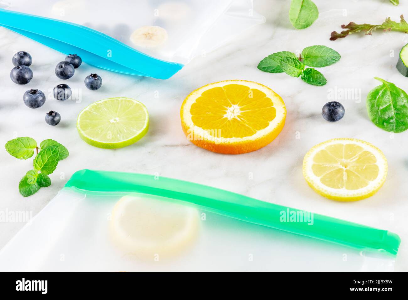 Lebensmittelbeutel mit Obst und Gemüse, auf einem Küchentisch aus weißem Marmor. Frische Sommerprodukte in Ziplock-Behältern Stockfoto