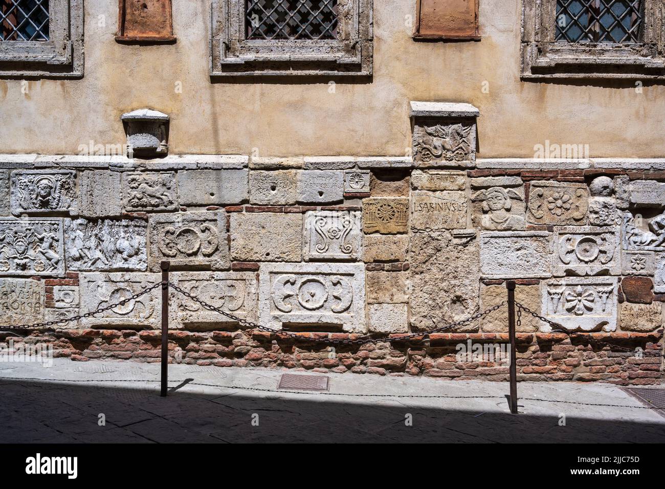 Alte etruskische Reliefs und Grabeurnen an der unteren façade des Palazzo Bucelli in der Via di Gracciano Nel Corso in Montepulciano, Toskana, Italien Stockfoto