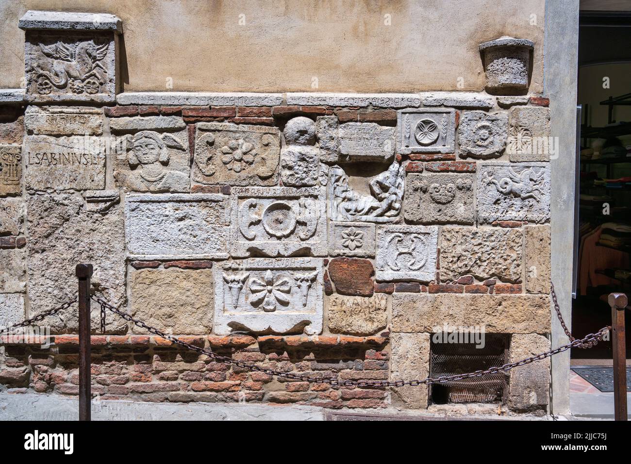 Alte etruskische Reliefs und Grabeurnen an der unteren façade des Palazzo Bucelli in der Via di Gracciano Nel Corso in Montepulciano, Toskana, Italien Stockfoto