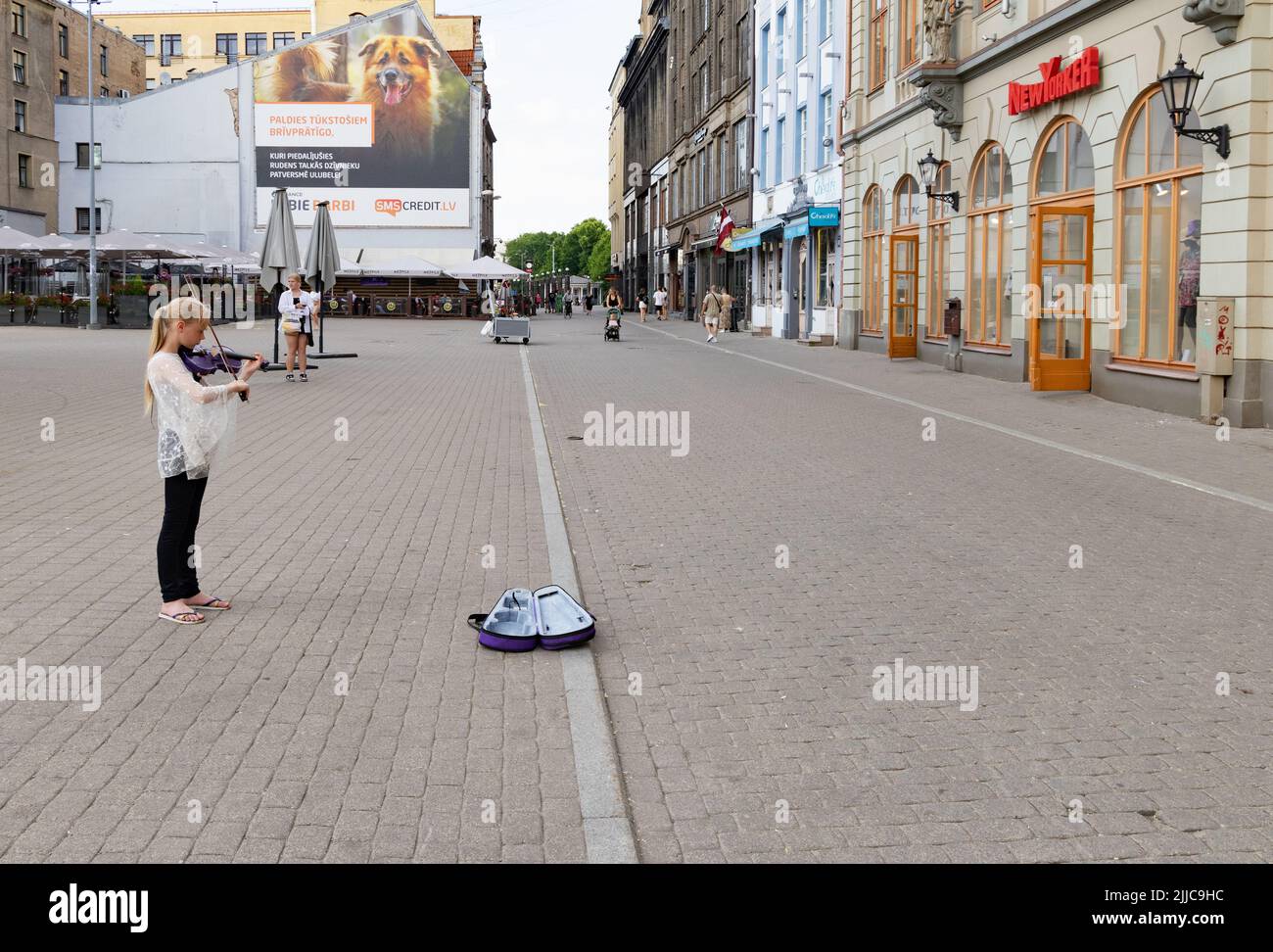 Kinder-Straßenmusikerin Riga; ein junges Mädchen im Alter von 10 Jahren, das auf der Violine musiziert, um Geld zu sammeln, Altstadt von Riga, Riga, Lettland, Europa Stockfoto