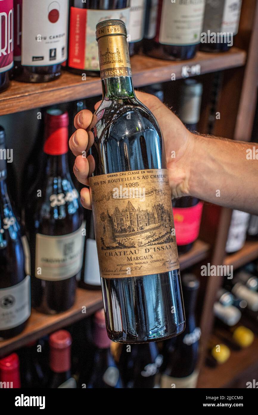 Die Hand des jungen Mannes hält eine teure Vintage-Rotwein-Flasche Stockfoto