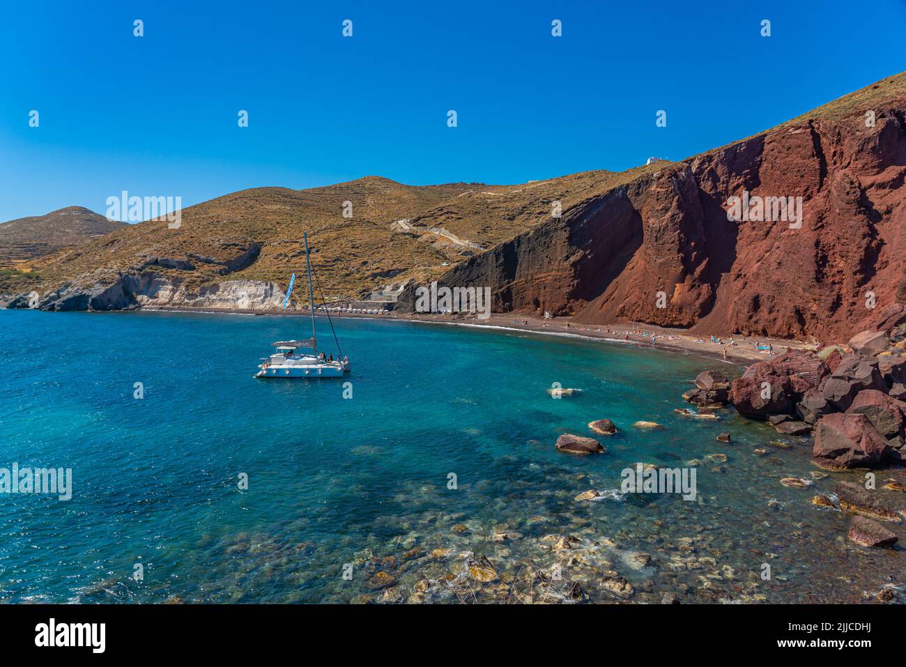Wunderschöne Landschaft von rotem Sandstrand mit einem Boot im Dorf Akrotiri auf Santorini, Griechenland Stockfoto