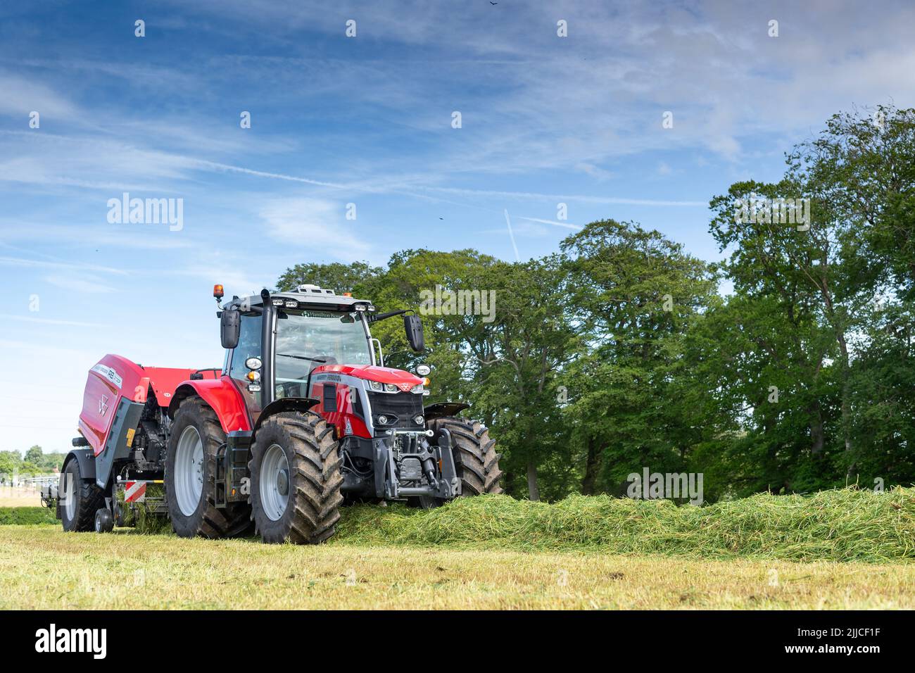 Großes Ballengras auf einer Wiese mit einem Massey Ferguson-Traktor und einer Ballenpresse mit Verpackung 3130DF. Dumfries, Schottland. Stockfoto