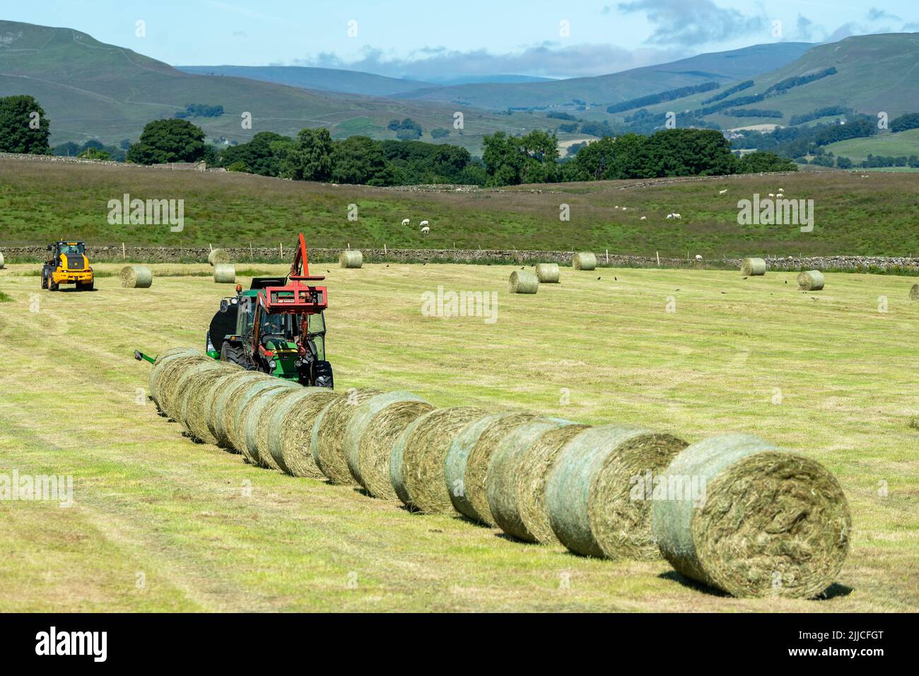 Bauer wickelt Silageballen nach dem Pressen im Sommer ein. Wensleydale, North Yorkshire, Großbritannien. Stockfoto