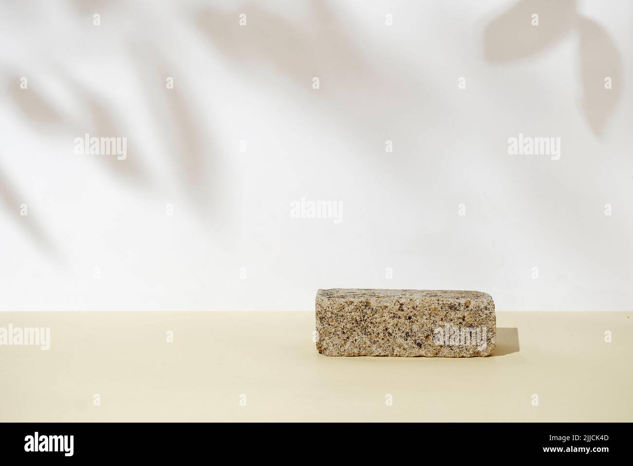Podestsockel aus Stein für Produktdemonstration. Blattschatten und natürlicher Pastellhintergrund. Das Konzept des neuen Naturalismus. Stockfoto