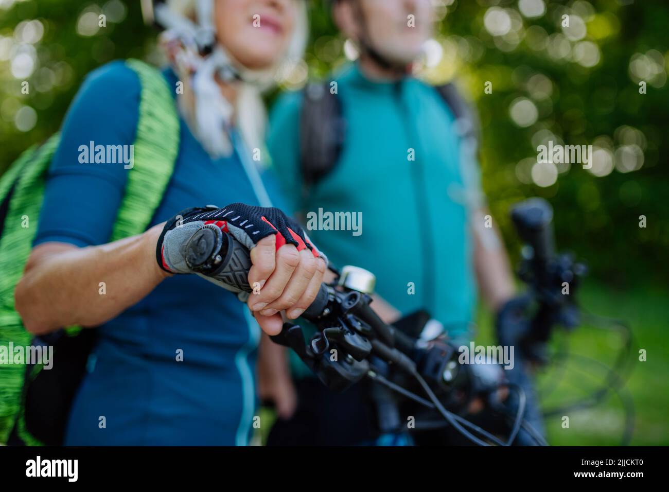 Nahaufnahme eines älteren Paares, das Fahrräder fährt, eine Bikerin, die sich am Lenker festhält. Stockfoto