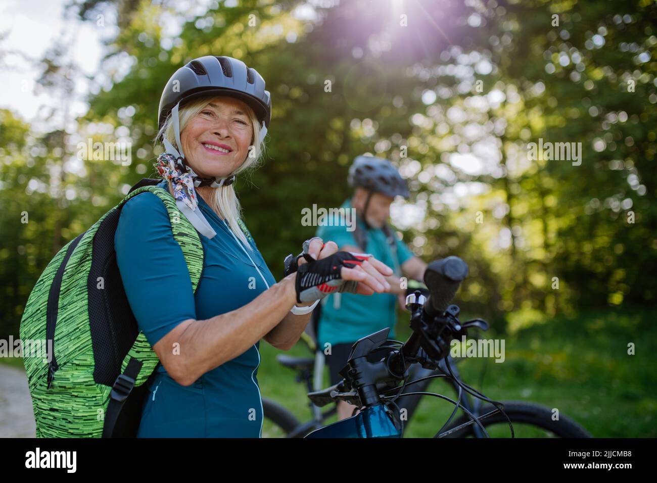 Glückliche ältere Frau Biker, die Fahrradhandschuhe anziehen. Stockfoto