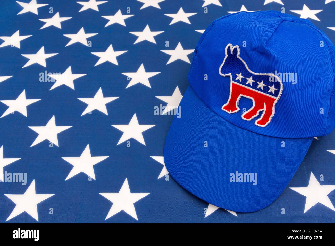 Blaue DNC-Kappe mit dem Esel-Emblem und US Stars and Stripes Flagge. Für die Präsidentschaftswahlen 2024 in den USA und die Vernichtung der Demokraten durch die republikanische Rote Welle. Stockfoto