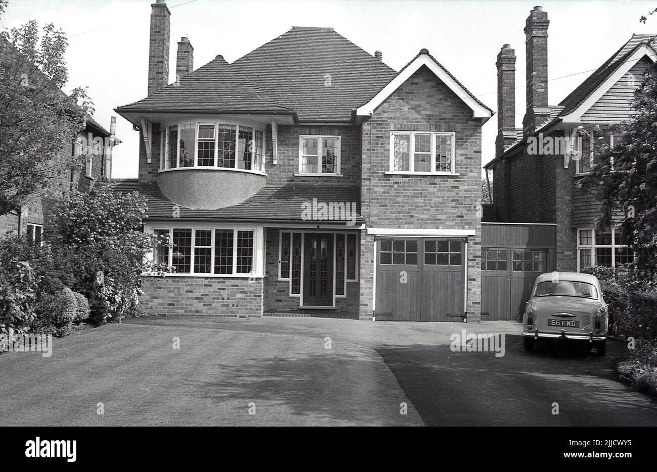 1970s, historisch, außen, Vorderansicht eines neu gebauten, großen, gemauerten freistehenden Vorstadthauses, England, Großbritannien. Auf der Auffahrt steht ein 1960s-er, ein Wolseley 1500, Stockfoto