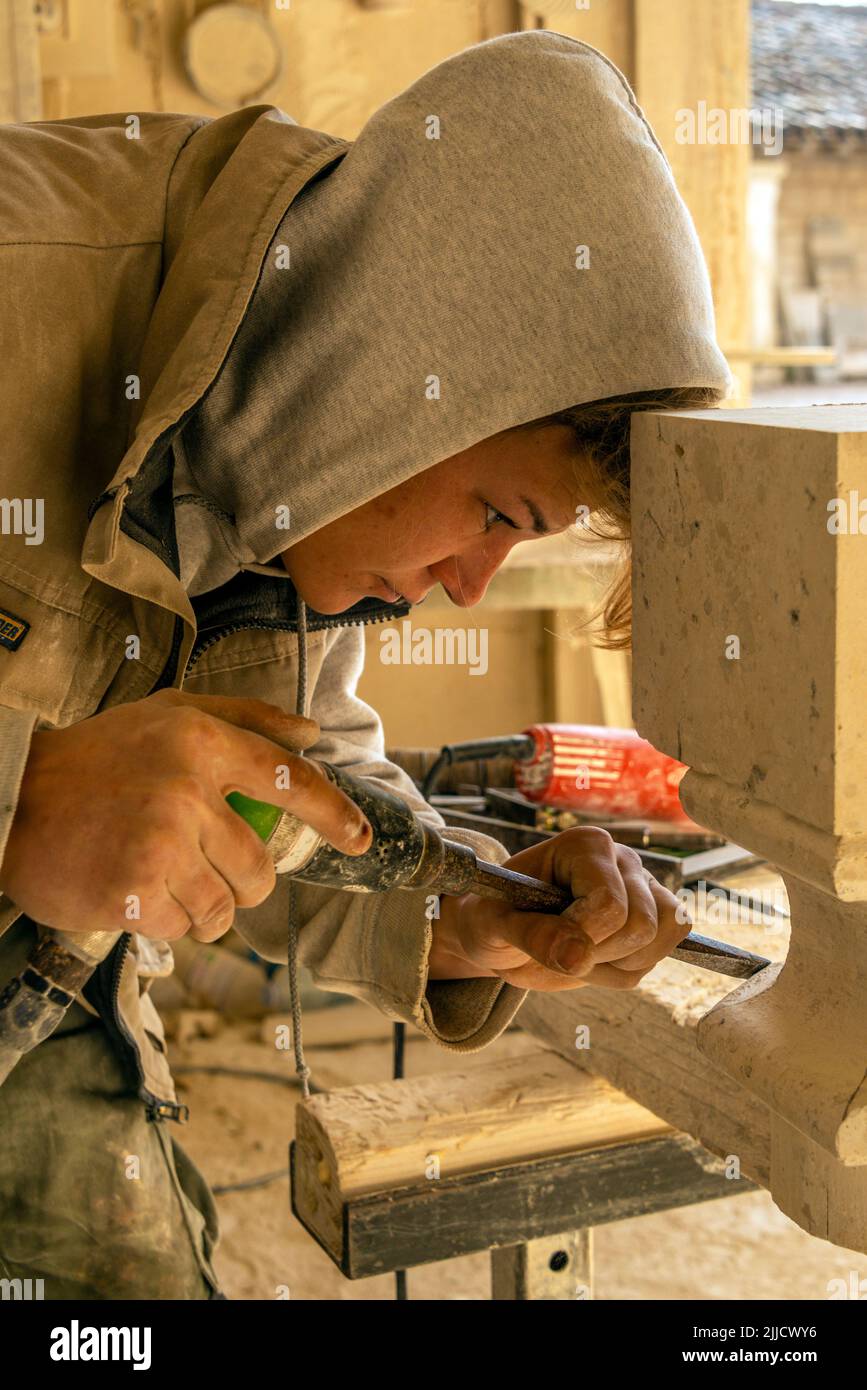 Weibliche Steinmetzschülerin bei der Arbeit Schneiden von Kalkstein Stockfoto