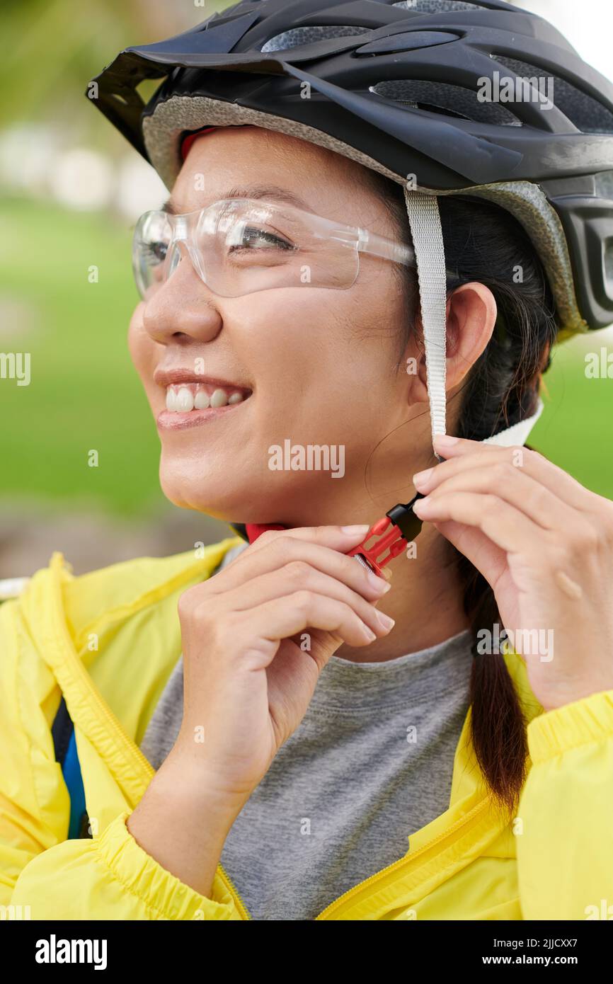 Glückliche Radfahrerin, die Fahrradhelm aufsetzt, um im Park zu fahren Stockfoto