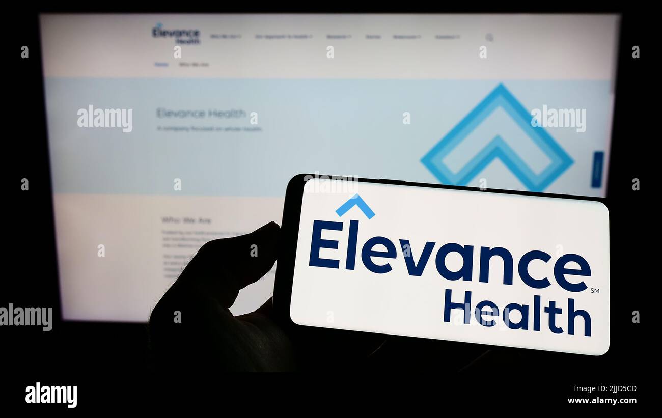 Person mit Mobiltelefon und Logo der amerikanischen Versicherungsgesellschaft Elevance Health Inc. Auf dem Bildschirm vor der Webseite. Konzentrieren Sie sich auf die Telefonanzeige. Stockfoto