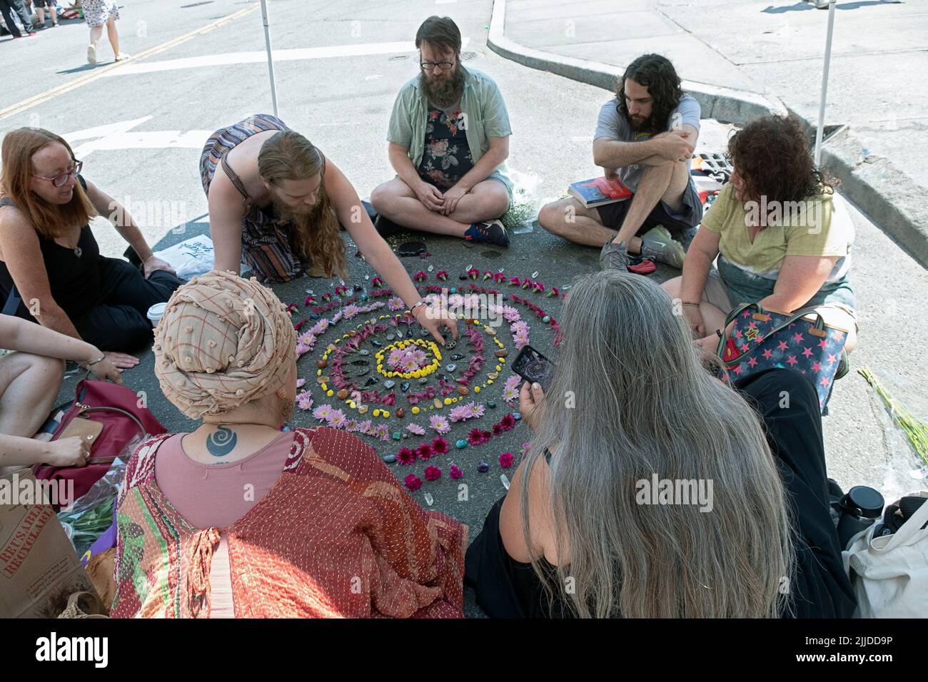 Männer und Frauen umgeben ein Mandala aus Kristallblumen, um ein buddhistisches Ritual des neuen Zeitalters durchzuführen. Beim Withcsfest 2022 in Greenwich Village. Stockfoto