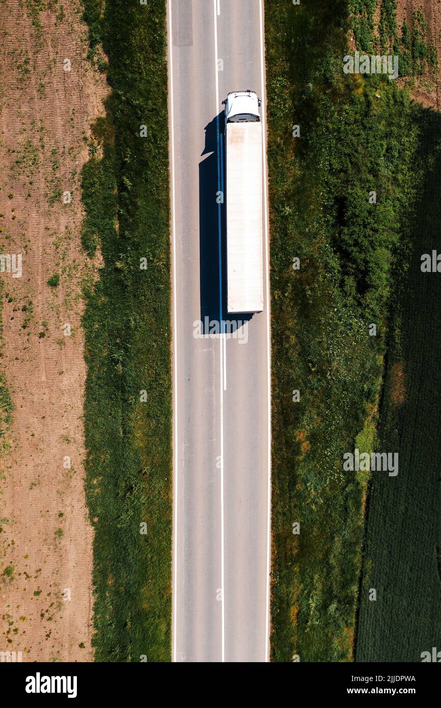 Luftaufnahme von Sattelschlepper, die entlang der Autobahn durch die Landschaft fahren, Drohne pov direkt oben am sonnigen Frühlingstag. Transport und lo Stockfoto