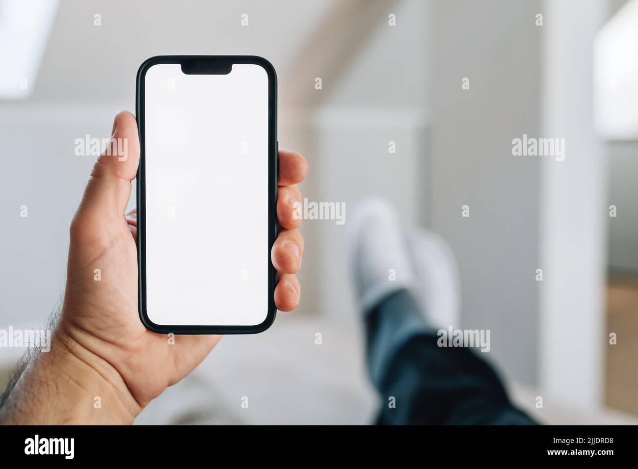 Smartphone-Mockup, Internet der Dinge und Smart-Home-Konzept, Mann mit Mobiltelefon. Nahaufnahme der Handhaltevorrichtung mit leerem Bildschirm im Home Interi Stockfoto