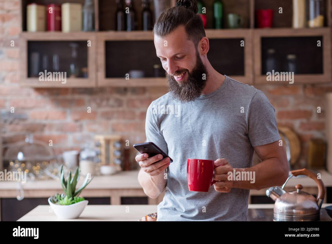 Morgen Gewohnheit Mann Küche Tee Kaffee überprüfen Telefon Stockfoto