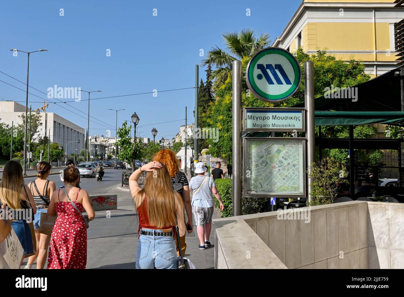 Athen, Griechenland - 2022. Mai: Menschen, die an einem Schild über dem Eingang der Megaro Moussiki Station, einer der U-Bahnstationen der Stadt, vorbeigehen Stockfoto