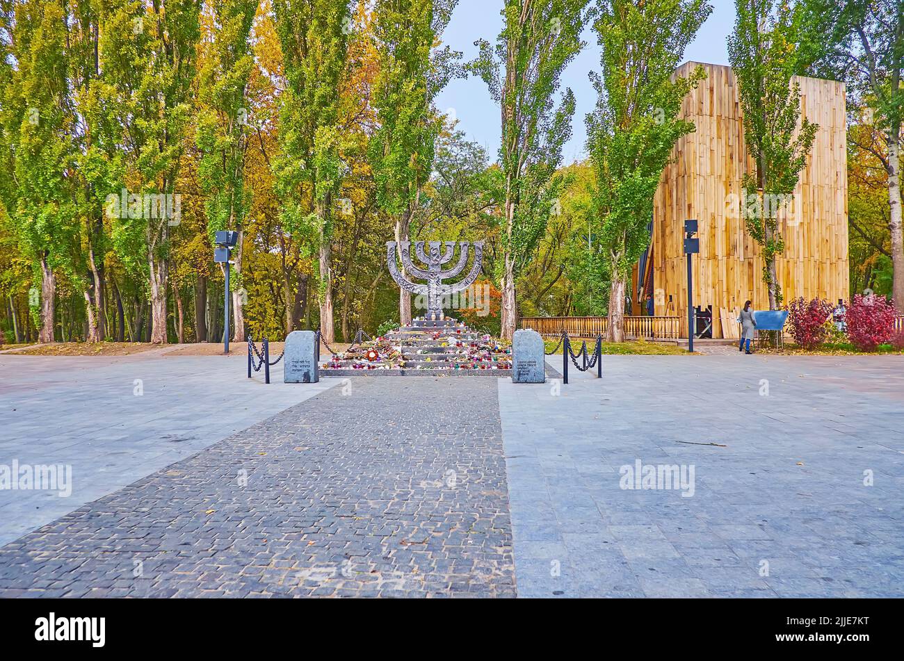 Der Platz mit dem Menorah-Denkmal und den Herbstpappeln im Hintergrund, der Holocaust-Gedenkpark Babyn Yar, Kiew, Ukraine Stockfoto