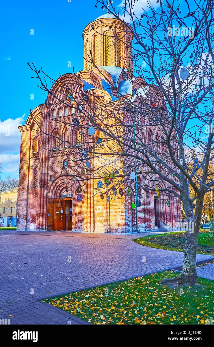 Die malerische Backsteinkirche St. Paraskeva (Pjatnytska) hinter dem Baum mit hängenden Papierdekorationen, Tschernihiw, Ukraine Stockfoto