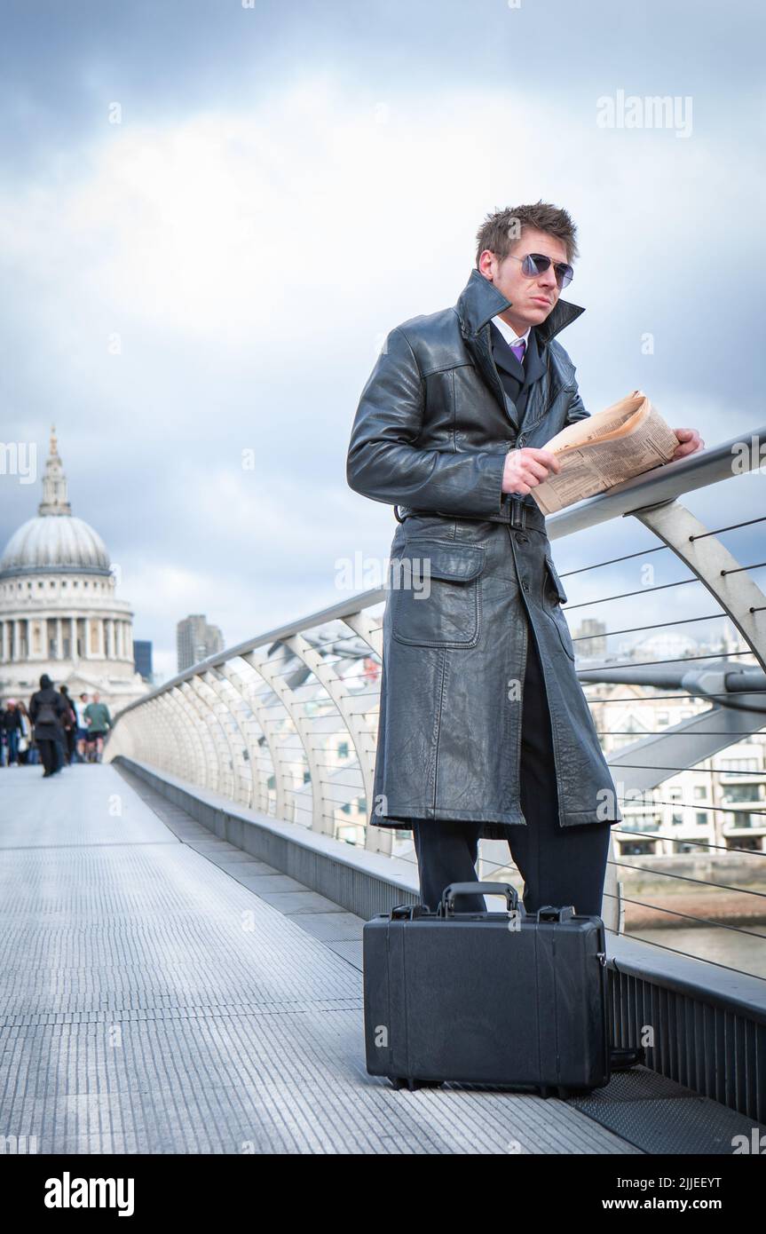 Undercover Agent; London Bridge. Ein Spion, der auf der Millennium Bridge in London lässig auf seinen Kontakt wartet; aus einer Serie von Bildern mit demselben Charakter. Stockfoto