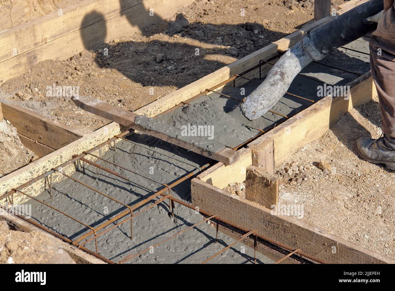 Bauarbeiter, der das Fundament des Hauses mit Betonmischung füllt Stockfoto