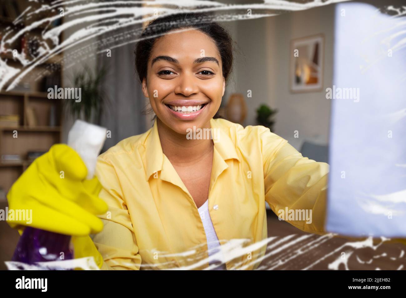 Schwarze Frau Reinigung Fenster Glas Mit Rag Und Reinigungsmittel Innen Stockfoto