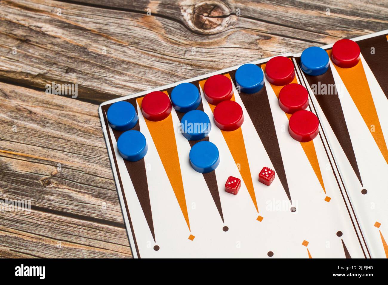 Ein Backgammon-Brett mit roten und blauen Steinen und kleinen Würfel auf einem Holztisch Stockfoto