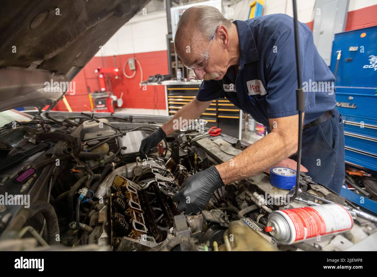 Aurora, Colorado - Russell Bacon behebt das Ölleck eines Autos durch die Hände des Carbenters. Die gemeinnützige Organisation repariert Fahrzeuge, die alleinerziehenden Müttern gehören, bei der Reduzierung Stockfoto