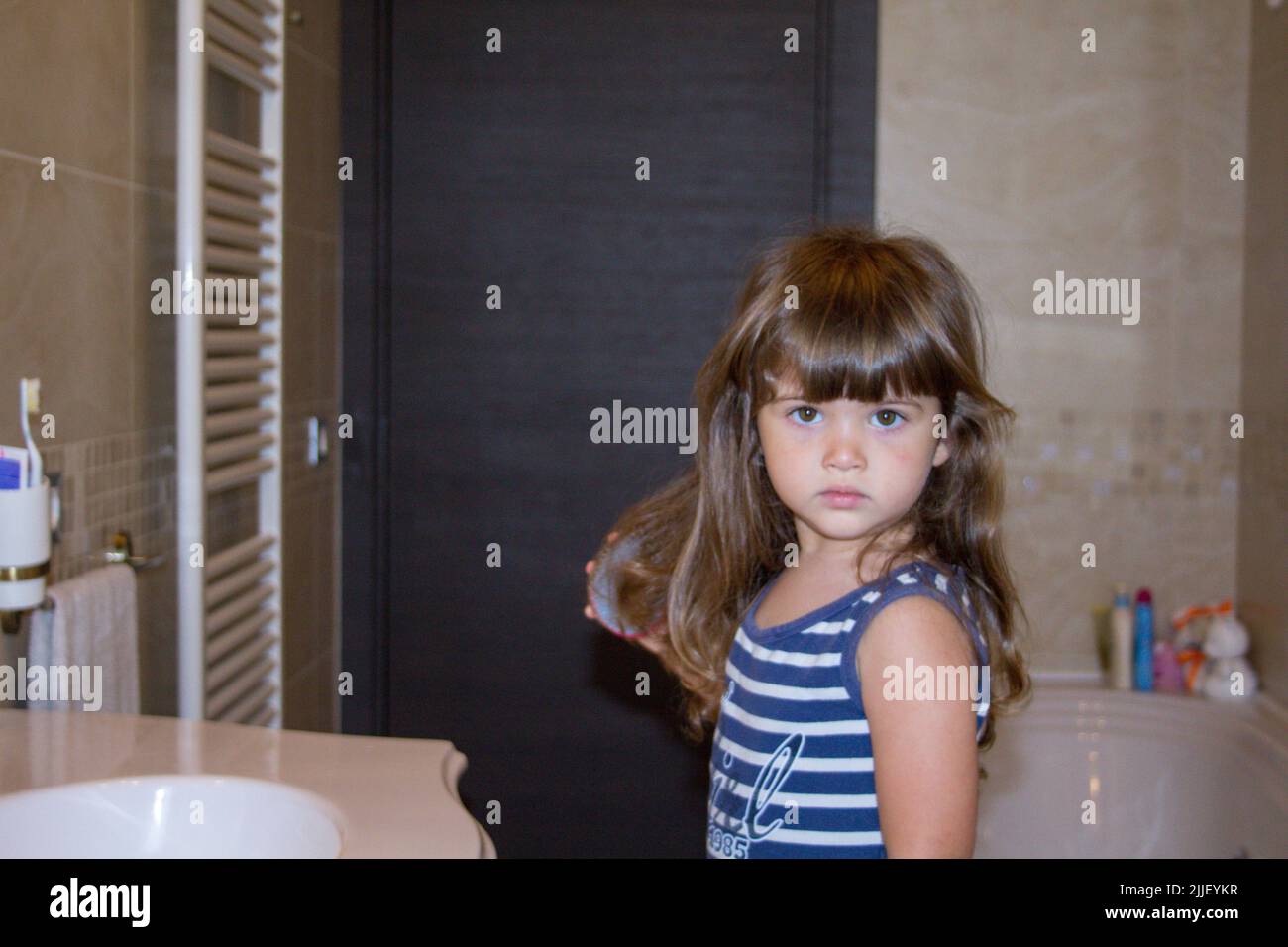 Bild von einem entzückenden kleinen Mädchen kämmen ihre Haare mit einer Baby-Bürste im Badezimmer Stockfoto