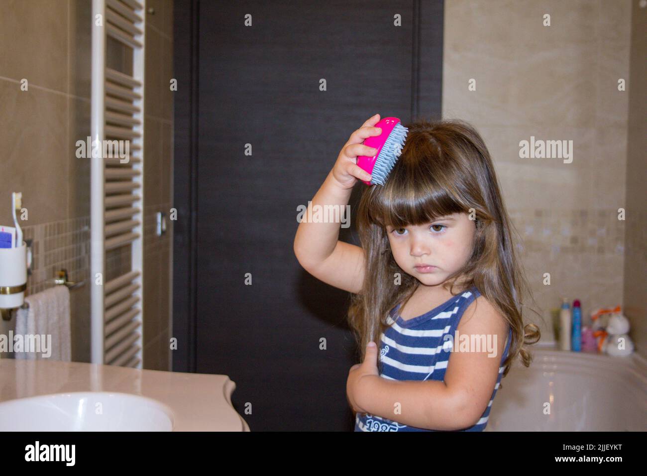 Bild von einem entzückenden kleinen Mädchen kämmen ihre Haare mit einer Baby-Bürste im Badezimmer Stockfoto