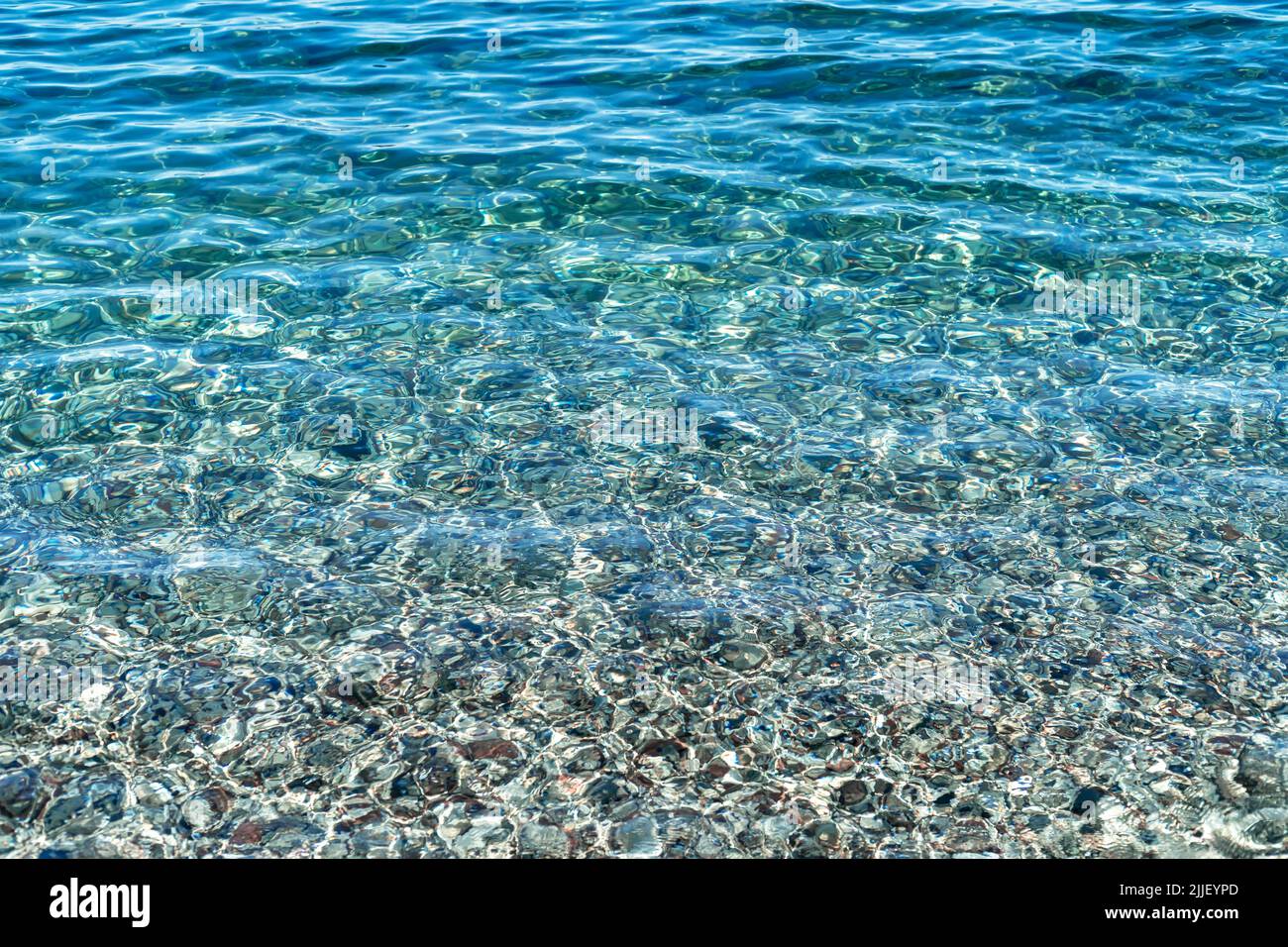 Nahaufnahme des kristallklaren Wassers des Olympos Strandes mit Kieselsteinen auf dem Boden in Antalya als Sommer, entspannen, ruhiger Hintergrund. Stockfoto