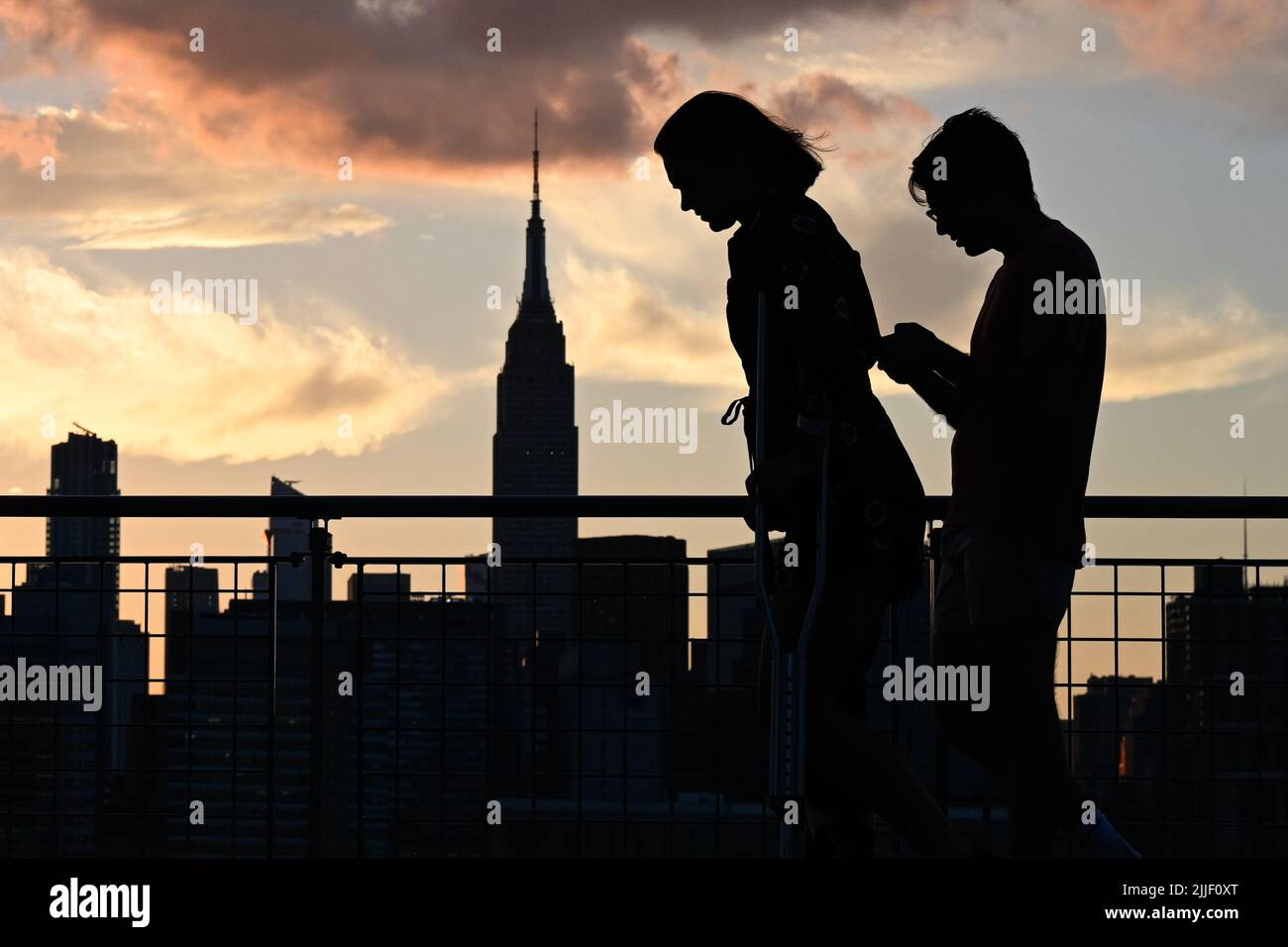 Auf dem Spaziergang entlang der Uferpromenade im Stadtteil Greenpoint in Brooklyn, New York, werden die Menschen vor der Skyline von Manhattan geschildet. Stockfoto