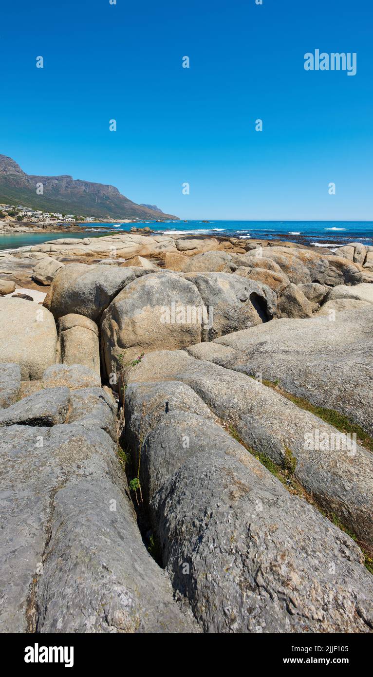 Landschaft, landschaftliche und Copyspace Blick auf Felsen und Felsbrocken am Meer oder an der Küste vor einem klaren blauen Himmel im Sommer. Wunderschön, friedlich und ruhig Stockfoto